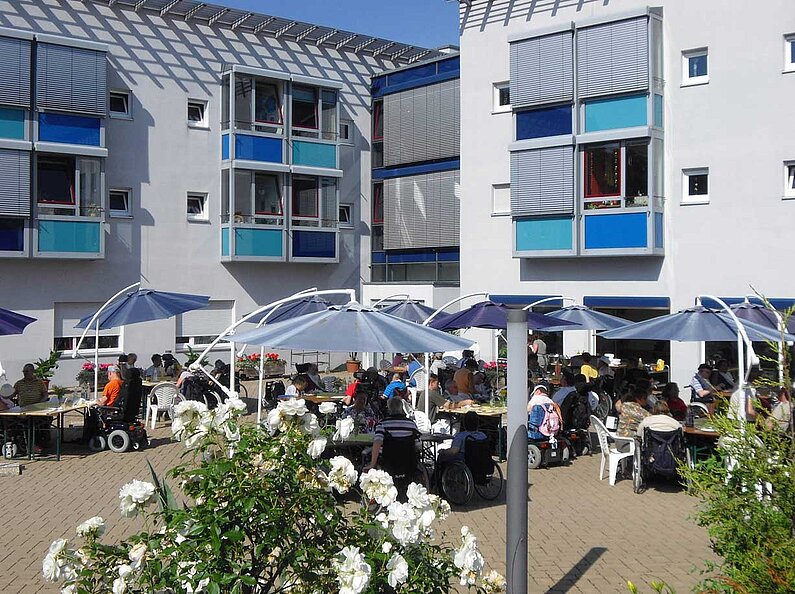 Viele Rollstuhlfahrer im Innenhof des Wohnzentrums im Sommer
