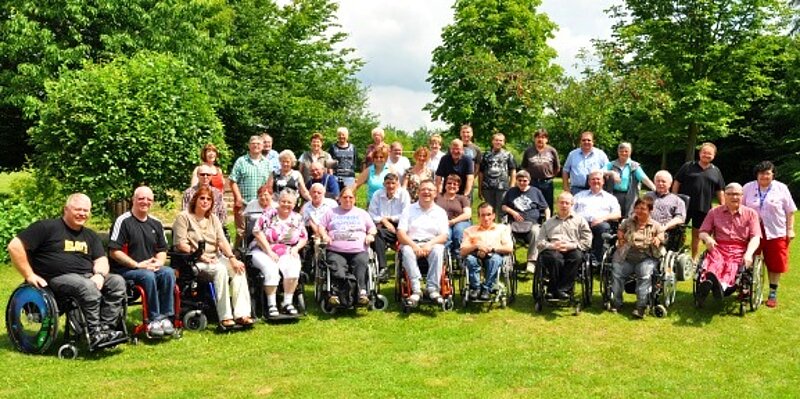 Gruppenfoto: Rollstuhlfahrende und Laufende in der Natur.