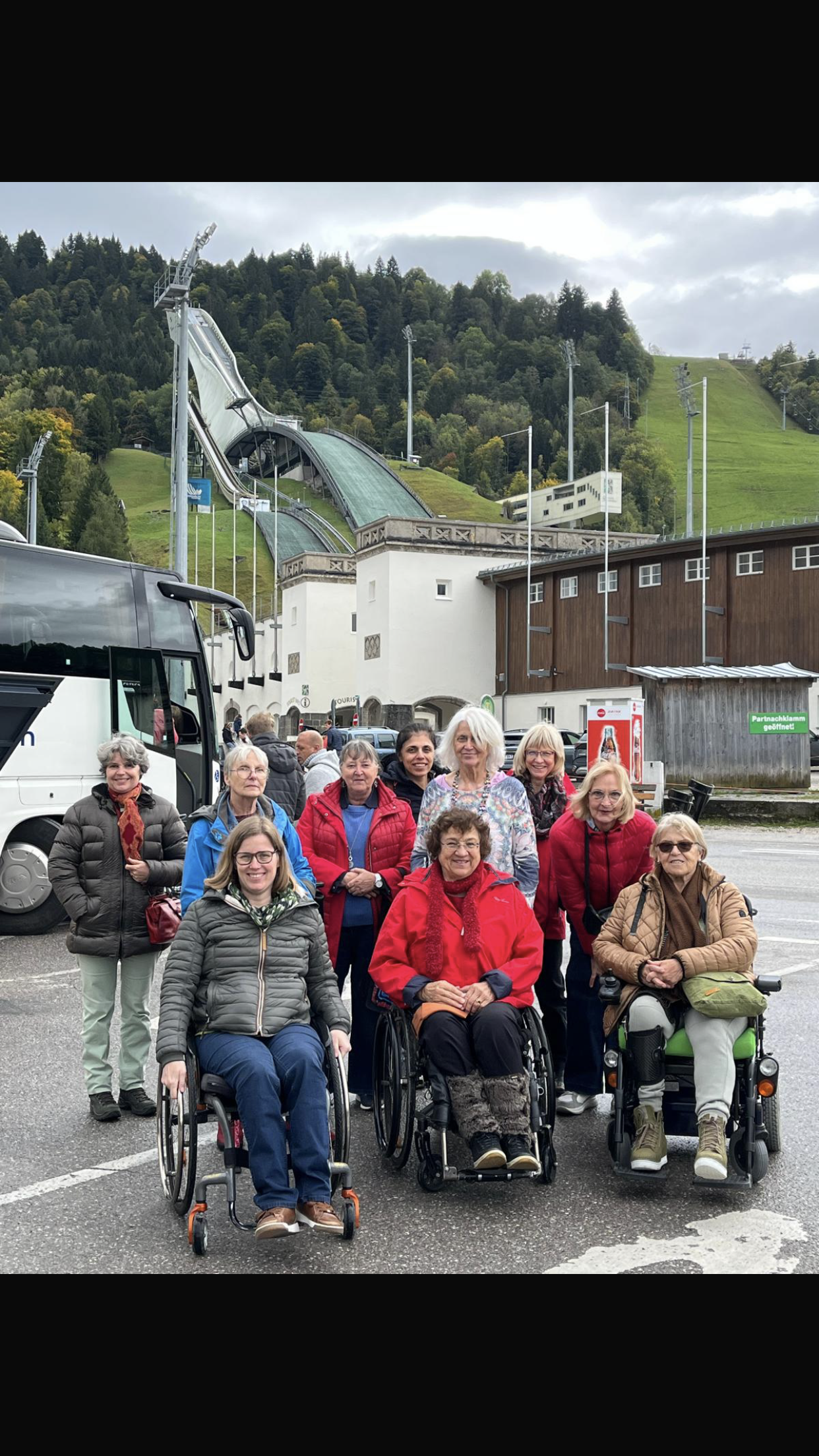 Gruppenfoto im Freien, drei Rollis, dahinter eine Skischanze